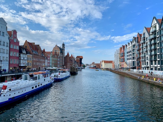 white boats on river besides town buildings in Neptune's Fountain Poland