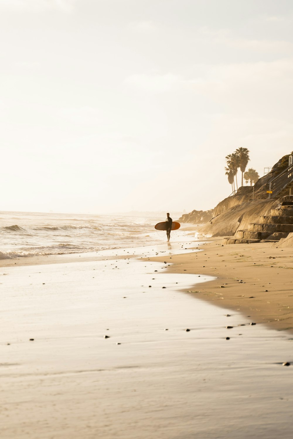 person standing while holding surfboard near seashore