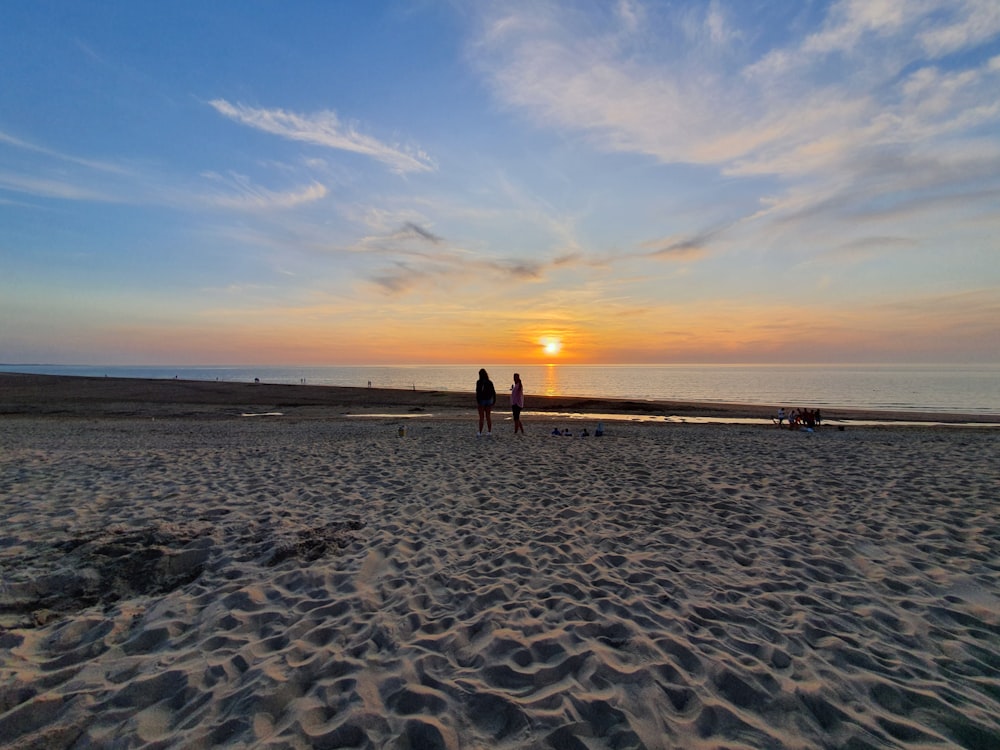 silhouette of two person standing beside seashore