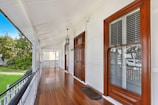 Elegant porch with classic southern architecture details, muted blues, and airy light filtering through lanterns and tailored millwork.