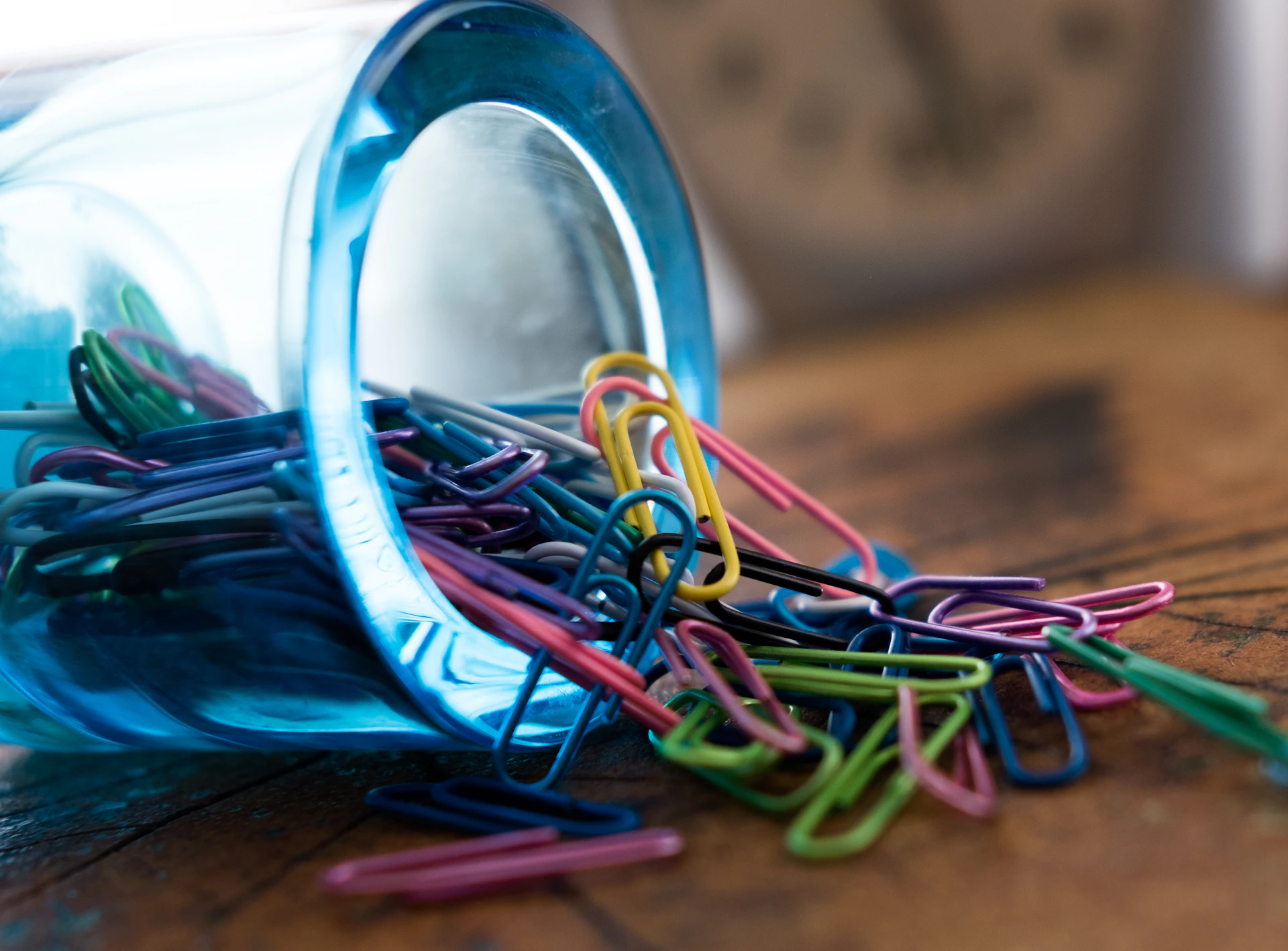 Close-up shot of colourful paperclips arranged in a gradient on a clean white surface, highlighting their smooth finish and vibrant hues.