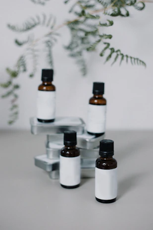 Close-up of handcrafted herbal tincture bottles nestled among fresh green leaves.