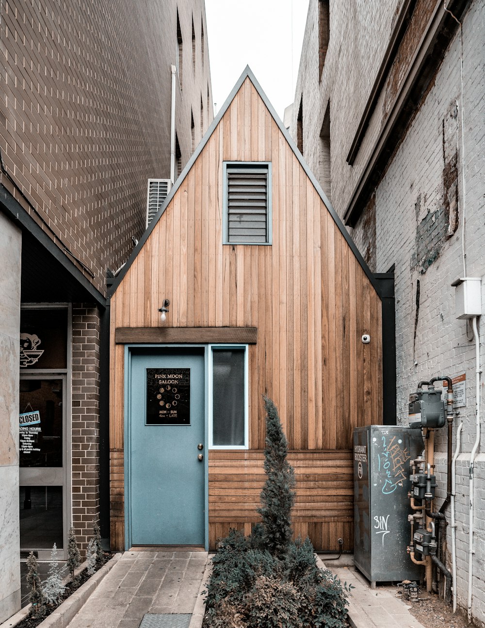 brown wooden house at the alley between buildings