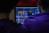 A mentor guiding a student through mixing on a large digital audio workstation screen.