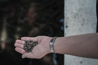Close-up of hands exchanging plastic pellets in a bright industrial setting.