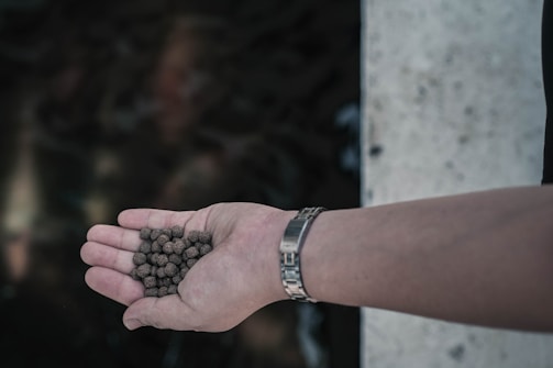 Close-up of hands exchanging plastic pellets in a bright industrial setting.