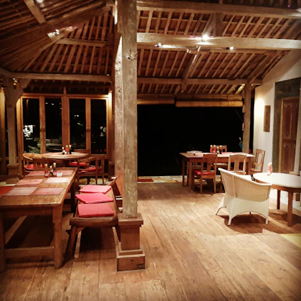 Cozy terrace dining with mountain views at sunset, featuring rustic wooden tables and warm ambient lighting.
