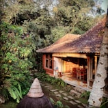 A beautifully crafted traditional joglo house made of teak wood in a lush garden setting.