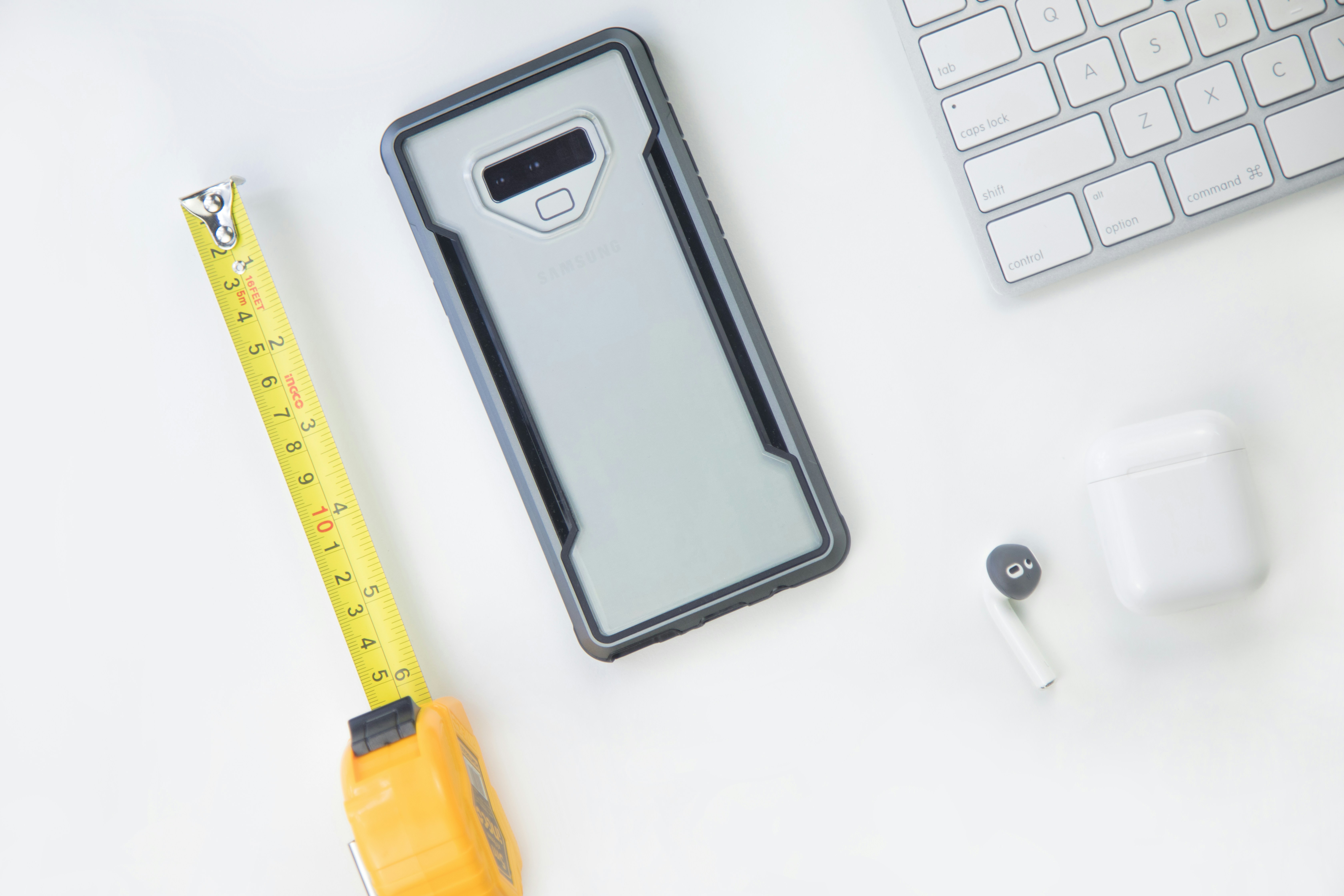 silver Android smartphone beside yellow tape measure