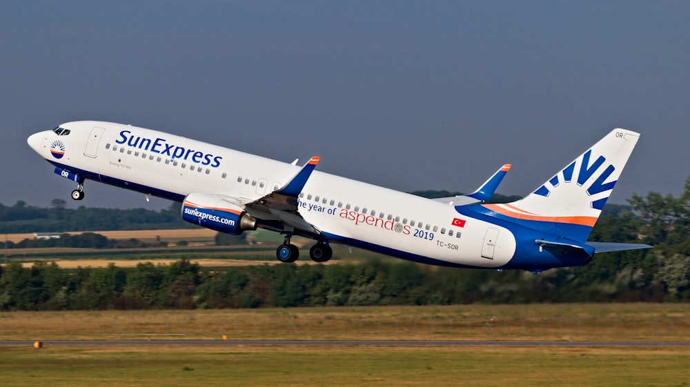 white and blue Sun Express passenger plane taking off from runway