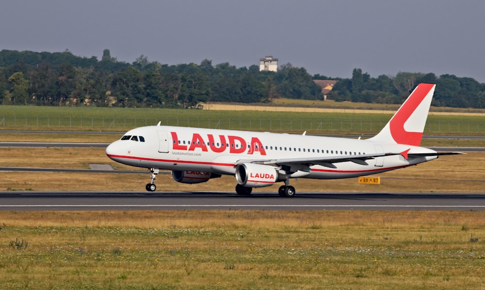 white and red Lauda airplane landing on railway
