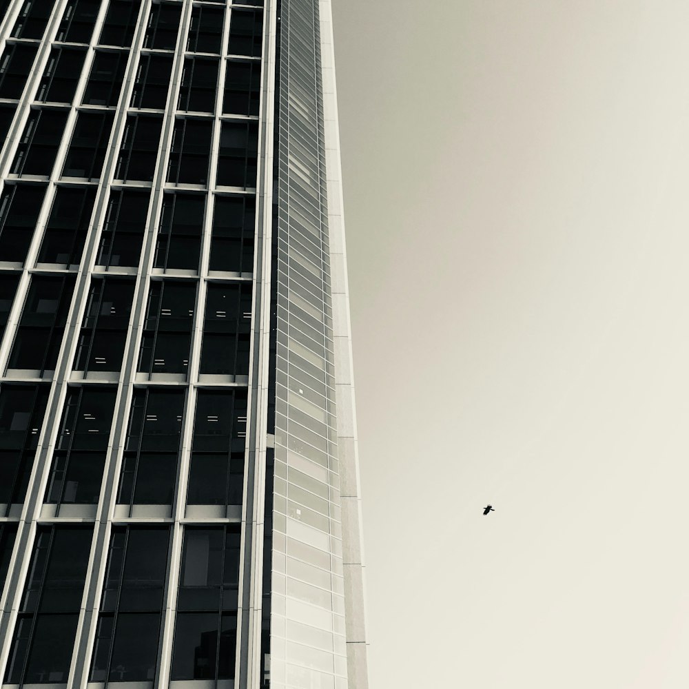 a plane flying in front of a tall building