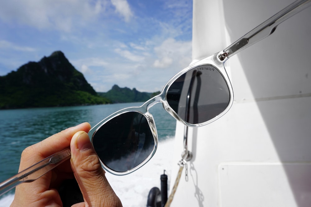 person holding black sunglasses with gray frames