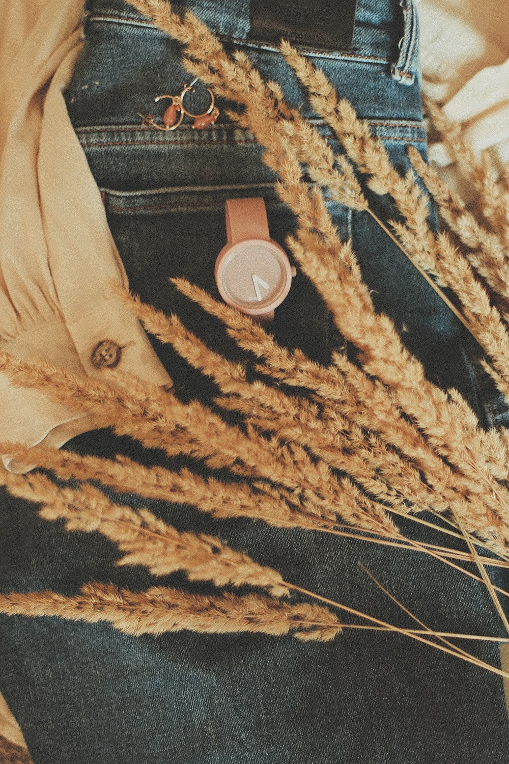 round brown analog watch on blue denim bottoms