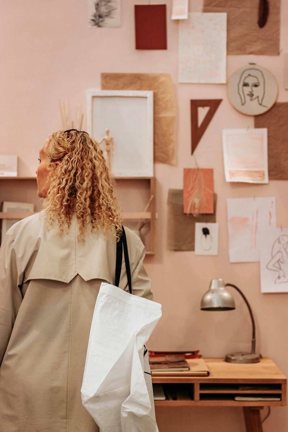 a woman holding a white bag in front of a wall