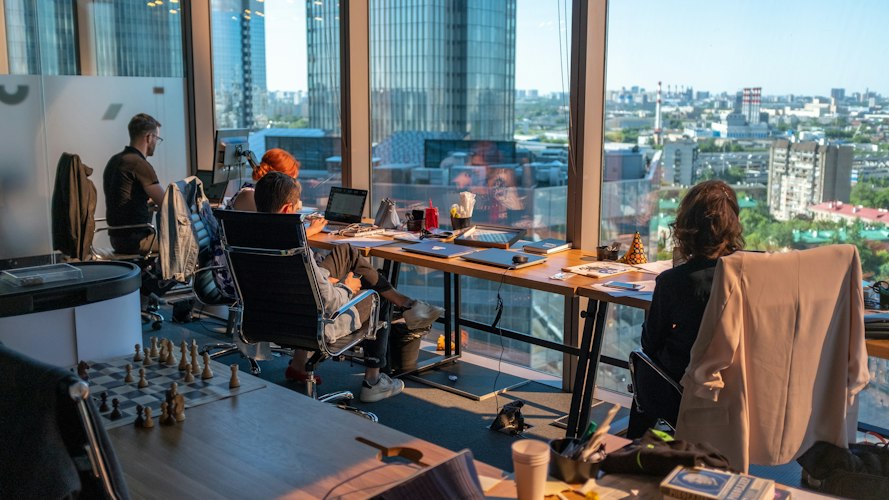 A group of colleagues collaborating around a laptop in a modern office