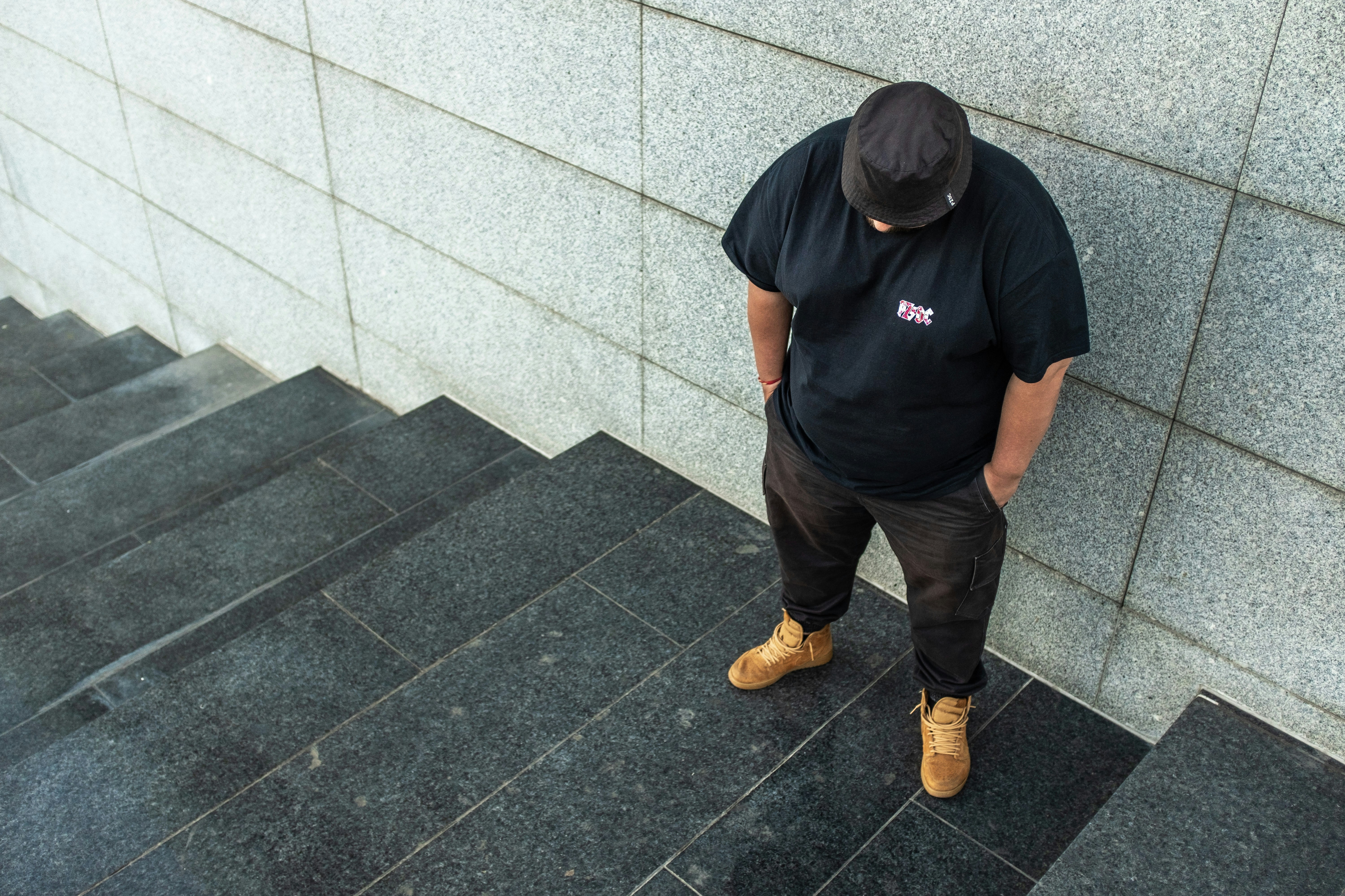 a man with hands in pocket wearing a hat