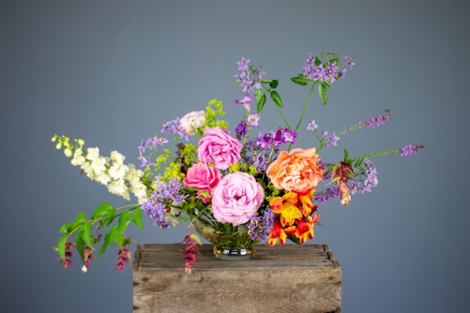 A colorful bouquet of fresh flowers arranged in a rustic vase on a wooden table.