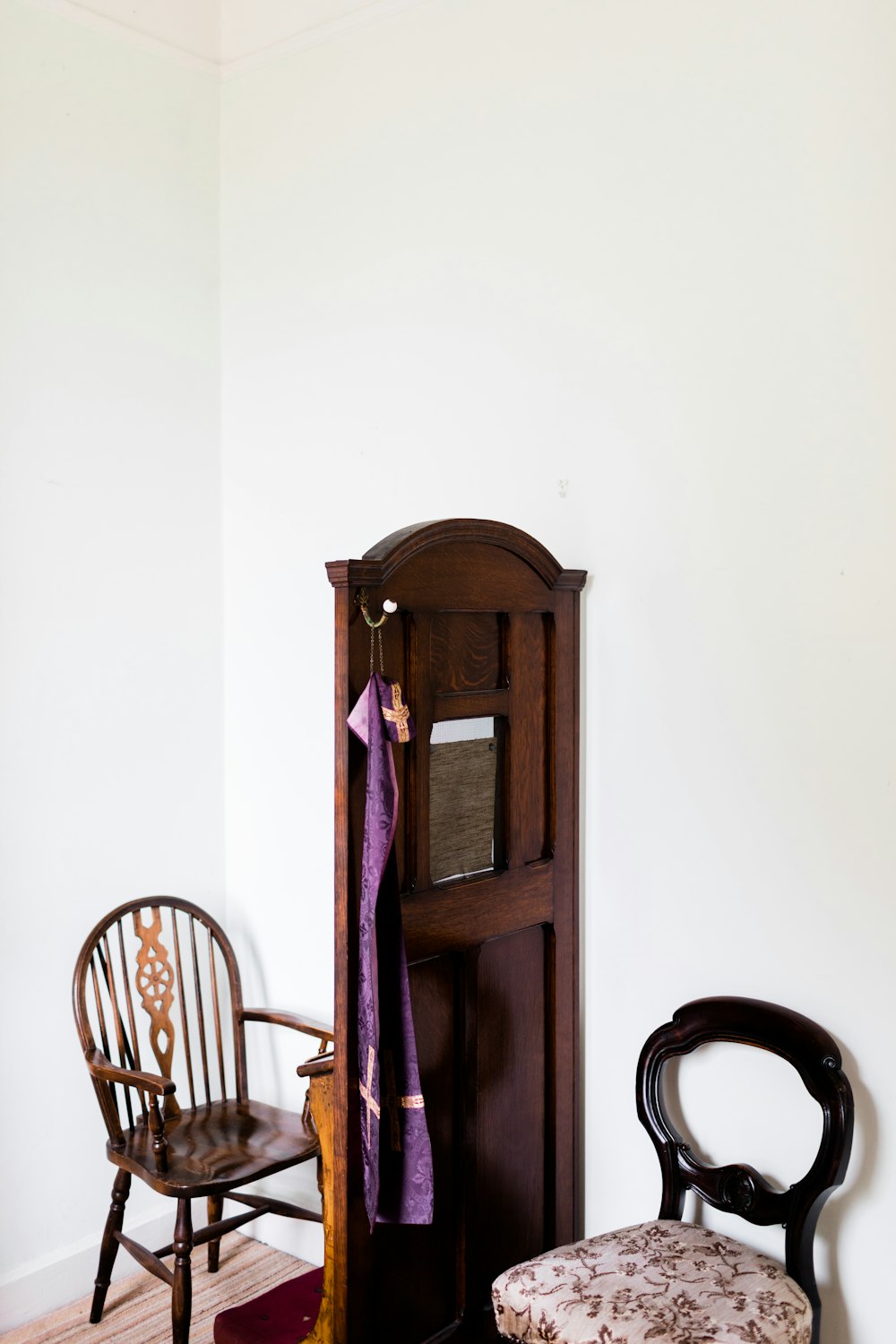 brown wooden cabinet beside brown wooden windsor armchair