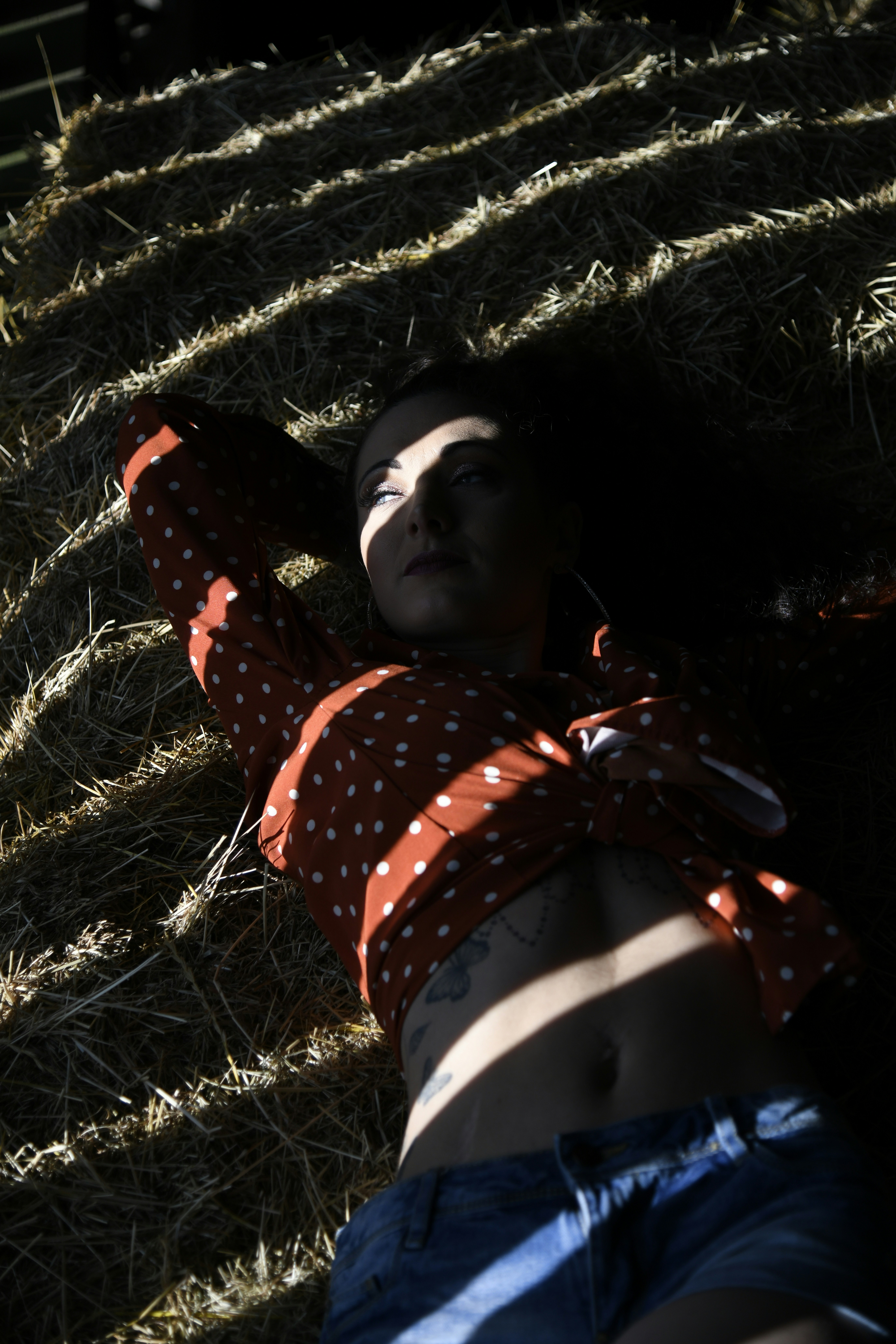 woman in red and white polka dots long-sleeved shirt lying on green grass lawn