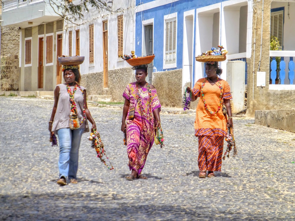 trois femmes portant un panier au-dessus de leurs têtes