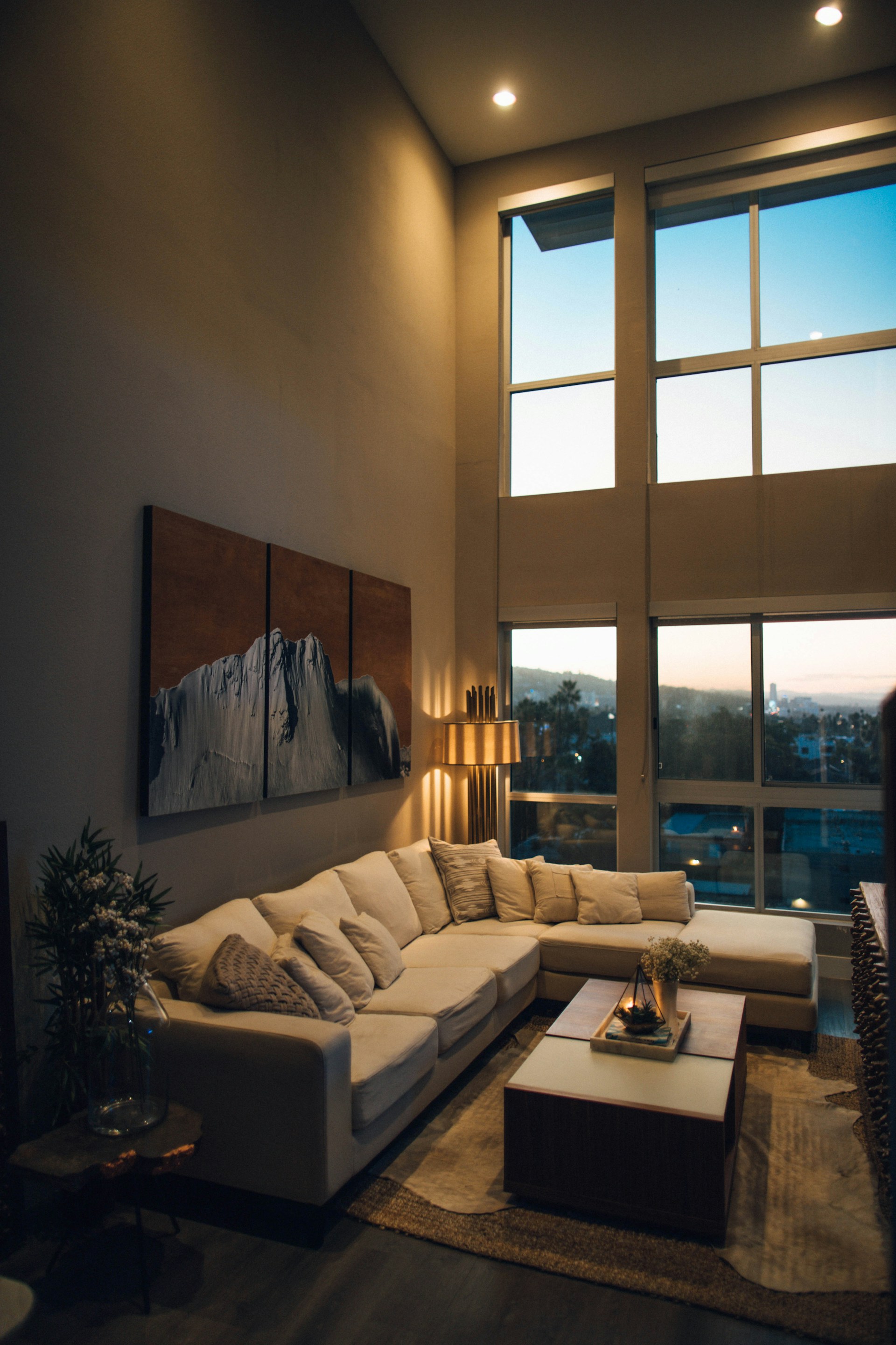 An evening living space with warm ambient light and floor-to-ceiling views