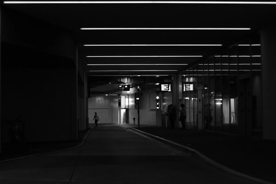 A solitary figure walks towards the camera down a dimly lit nighttime street
