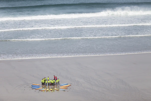 Group of friends laughing and wearing casual surfer-style clothing near the ocean.