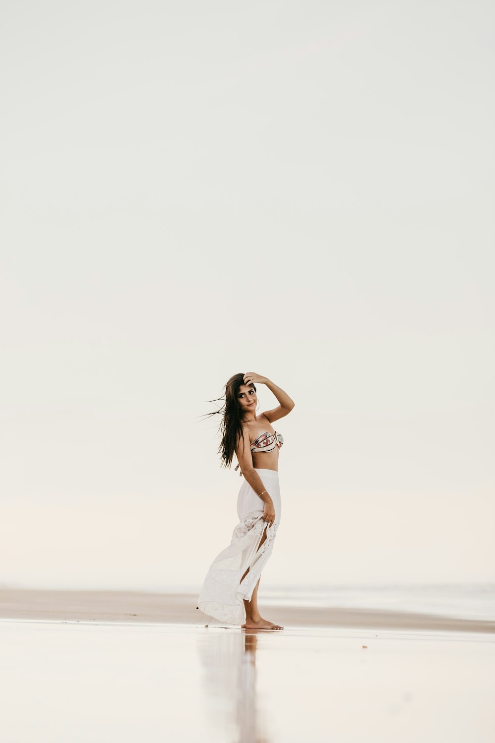 woman wearing white skirt standing on seashore