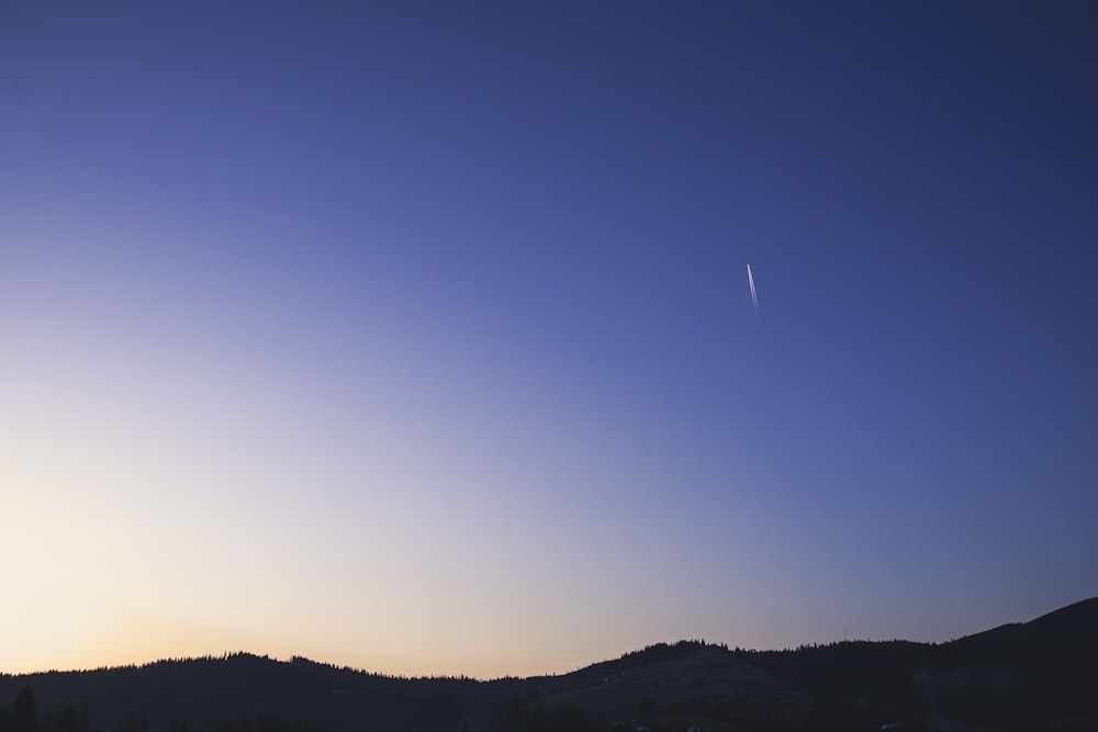 silhouette photo of mountain under blue sky during daytime