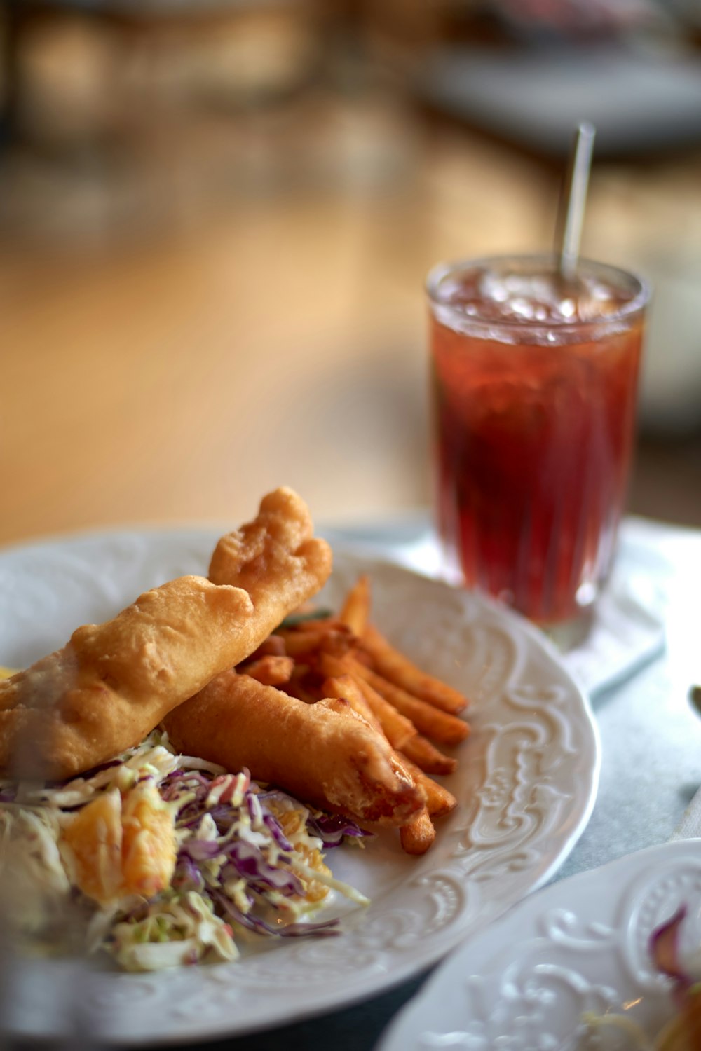 food on round white ceramic plate beside glass of drink