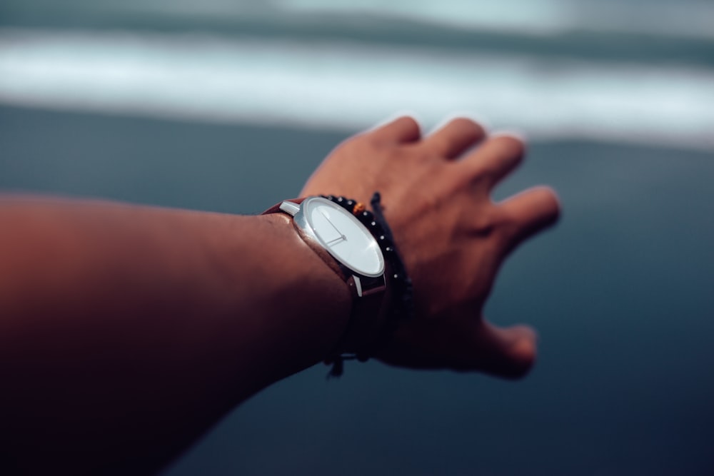 person wearing round silver colored analog watch