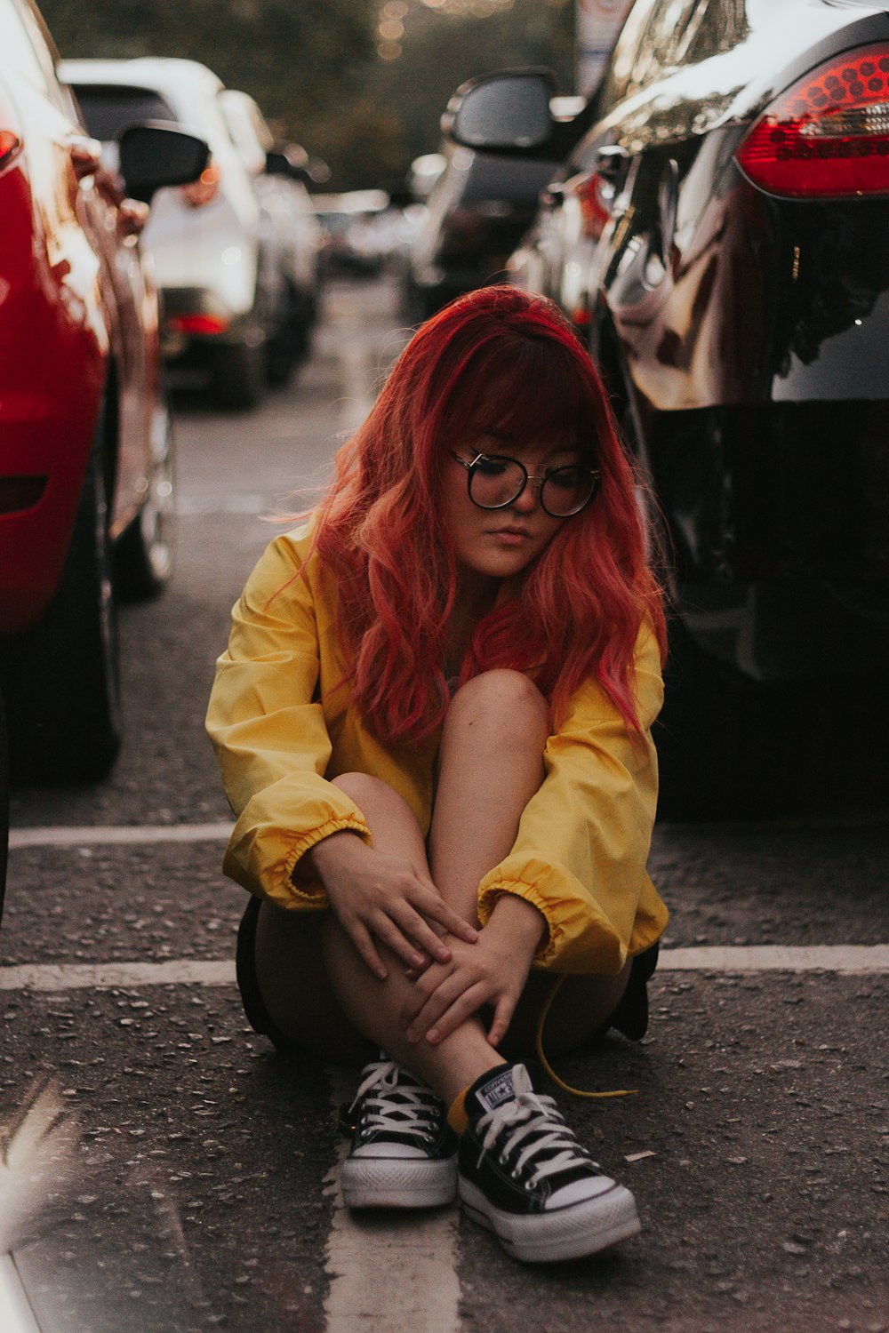 woman in yellow top sitting in between parked cars