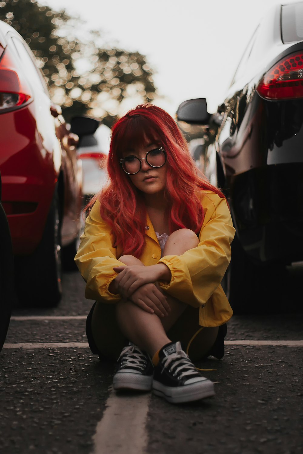 a woman with red hair and glasses sitting on the ground