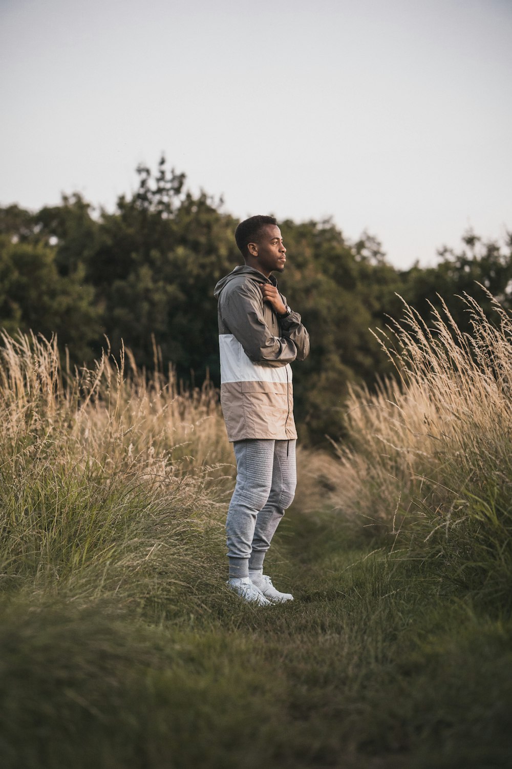 man wearing jacket and pants standing on grass field