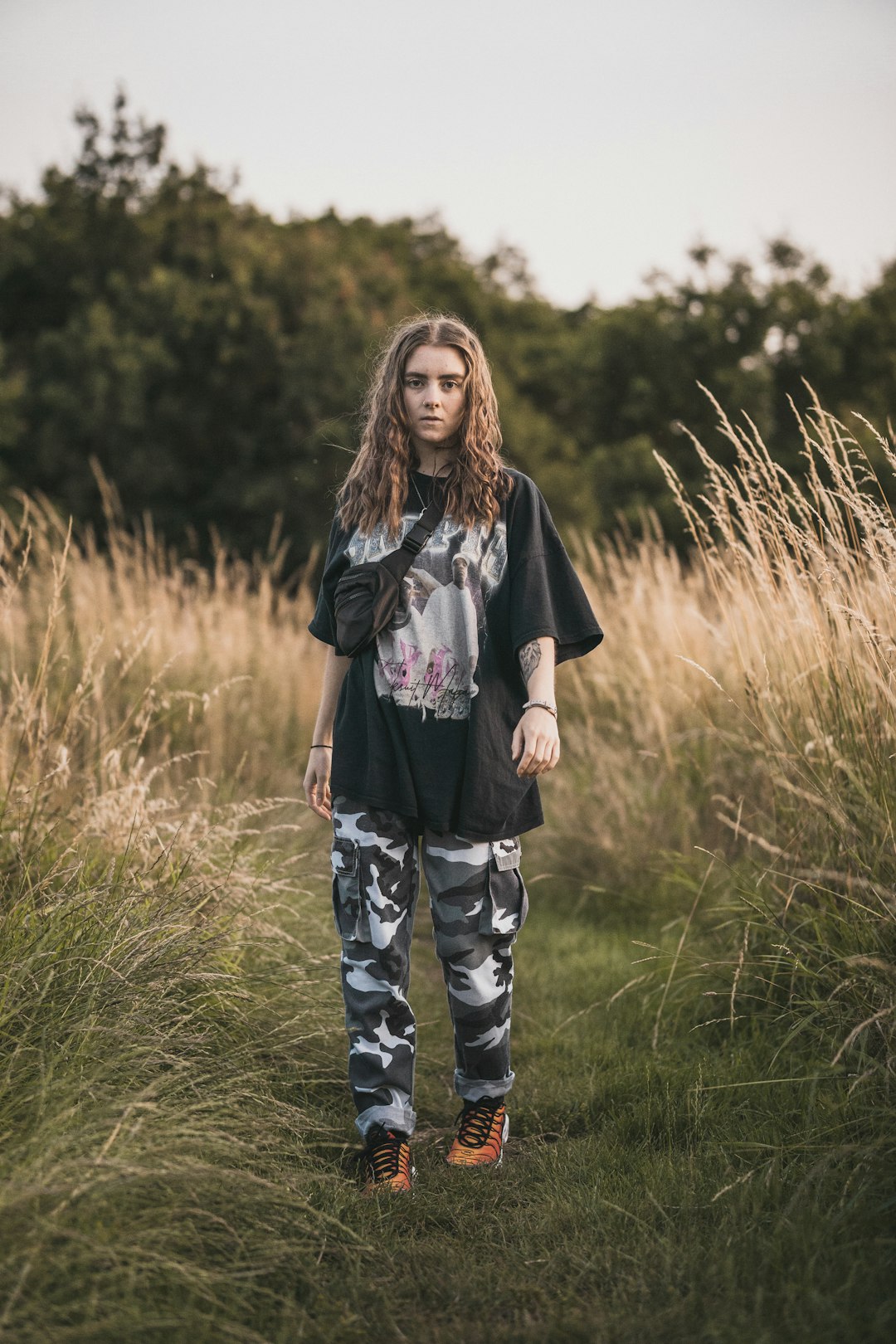 woman in black and grey t-shirt and grey camouflage pants standing in grassy trail