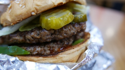 Close-up of a Big Pepe's burger with double smashed patties, sesame bun, and melted cheddar.