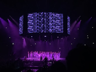 performers on a stage with violet lights