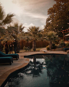 A small backyard pool with soft glowing lights and an integrated spa area nestled among wooden fencing.