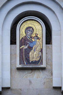 Artisan carefully placing tesserae on a religious icon mosaic in a sunlit studio.