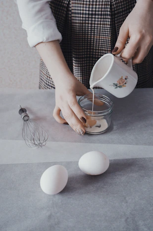 An overhead shot of a kitchen counter with baking ingredients and a mixing bowl mid-preparation.