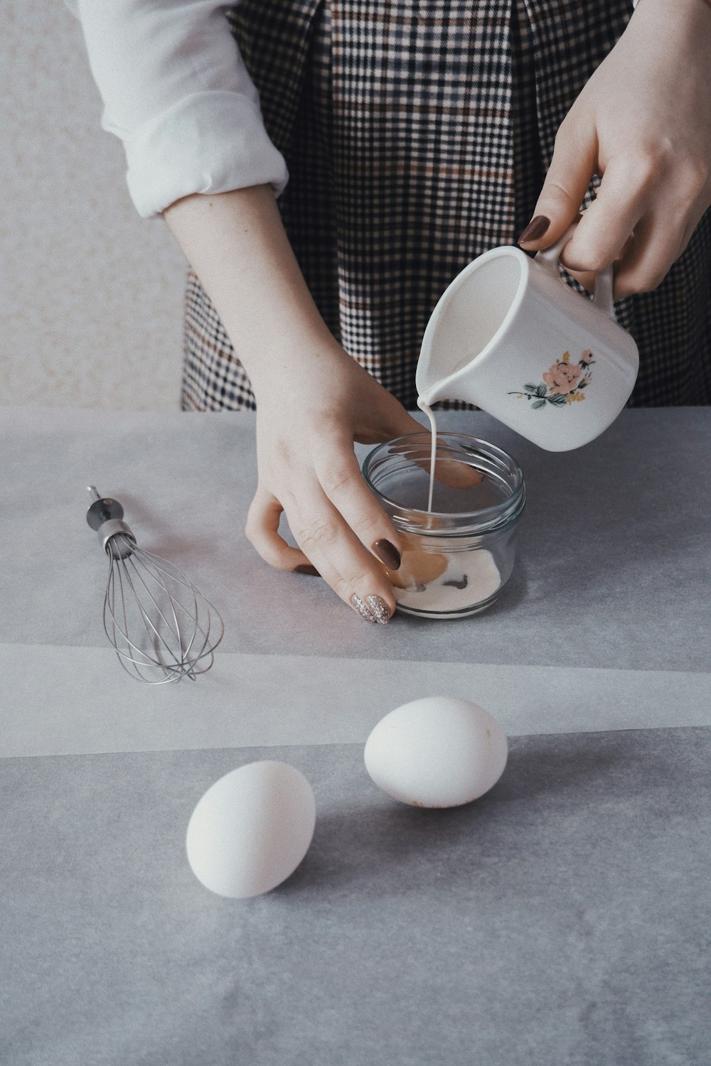 person pouring white liquid in jar