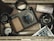 A collection of vintage photography equipment placed in a wooden box. There is a camera, a camera lens, photo slides, a roll of film, a currency note, a lens hood, and a small dial gauge. The items are arranged in an orderly, but casual manner giving a sense of nostalgia.