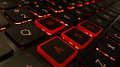 Close-up of hands on a keyboard with colorful game graphics on the screen.