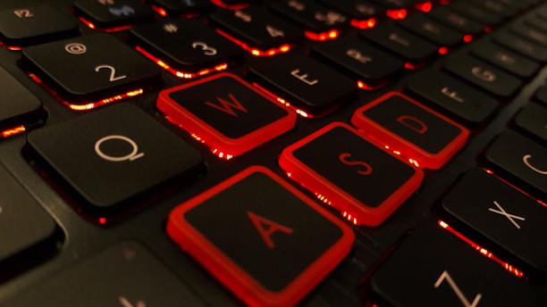 A close-up view of a computer keyboard featuring black keys with red backlighting, emphasizing the keys typically used in gaming contexts. The illuminated outlines create a striking visual contrast against the dark background.