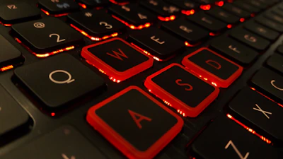 Close-up of a gamer’s hands on a red-backlit mechanical keyboard.