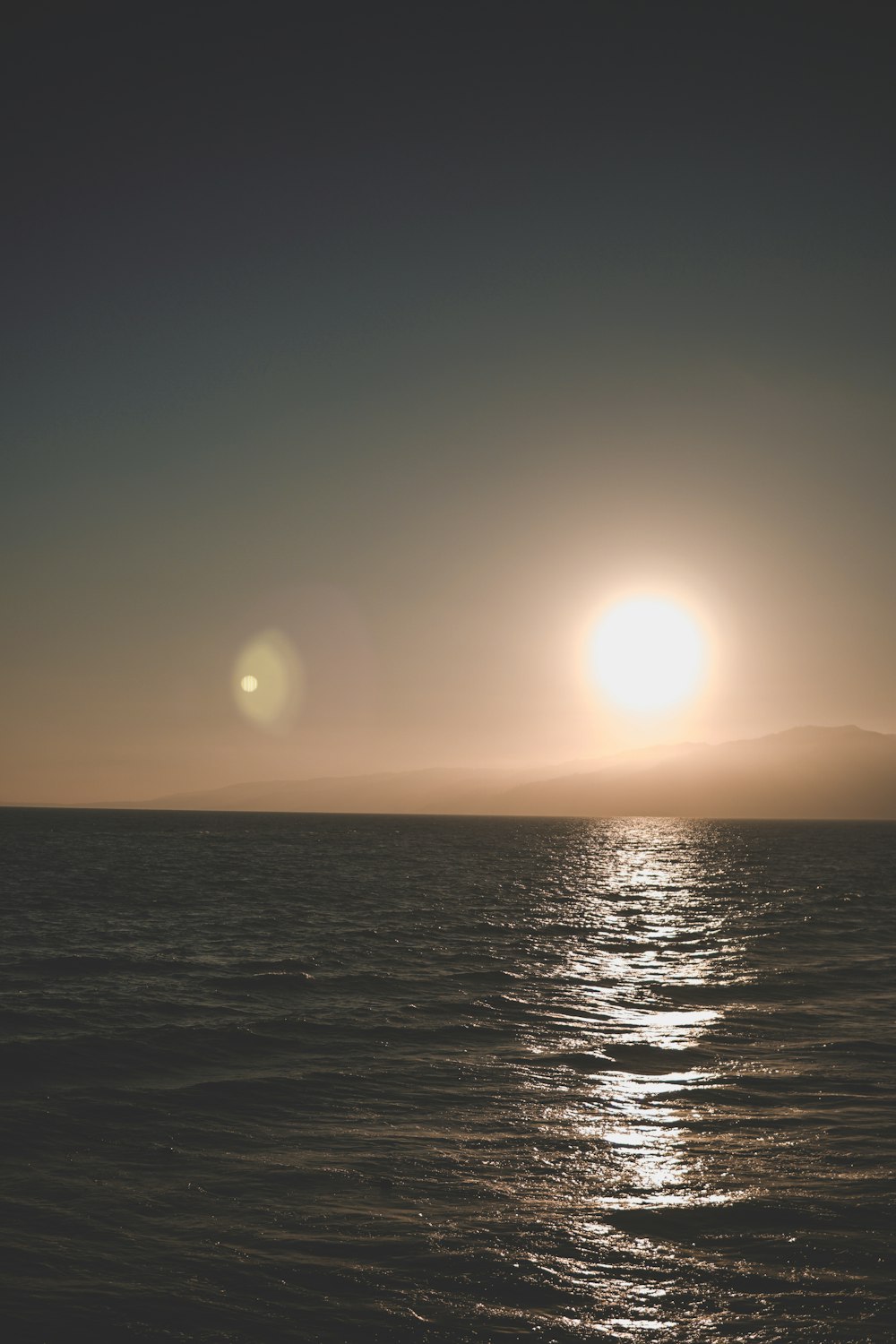 Un grande specchio d'acqua con un sole sullo sfondo