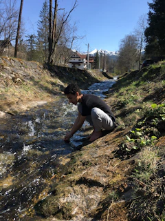 Engineers in the field measuring water flow in a mountain stream with specialized equipment.