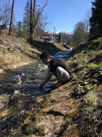 A close-up of hands carefully panning for gold in a clear mountain stream.