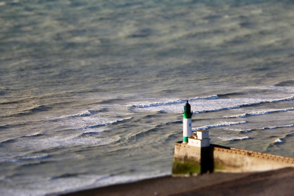 a green and white lighthouse sitting on top of a pier